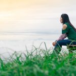 A woman being mindful and sitting by the water