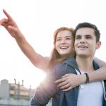 Happy woman holding her boyfriend and pointing