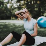 A woman tired from working out sitting down and wiping her forehead