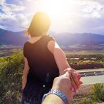 A woman holding her boyfriend's hand and walking in front of him