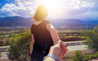 A woman holding her boyfriend's hand and walking in front of him