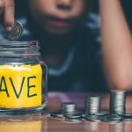 A woman putting money into a jar that says, 