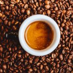 Full coffee mug on top of coffee beans