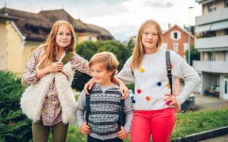 Group of 3 kids with backpacks, 2 schoolgirls and one preschooler, back to school concept
