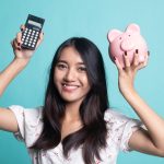 Young woman holding a piggy bank and calculator