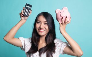 Young woman holding a piggy bank and calculator