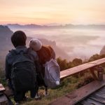 Two travelers leaning against each other over a beautiful valley