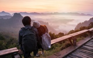 Two travelers leaning against each other over a beautiful valley