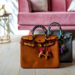 Two designer bags side by side in front of a couch