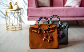Two designer bags side by side in front of a couch