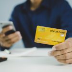 A man holding a credit card and a phone