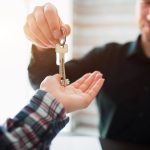 A landlord handing over a pair of keys to a tenent