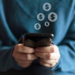A woman typing money signs on a smartphone