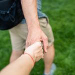 A couple holding hands on a grassy field