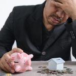 A disappointed man with coins and a piggy bank