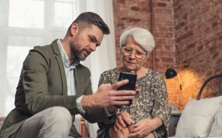A millennial showing a smartphone to a Baby Boomer