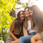 three female friends sitting together outside