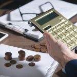 A calculator coins and glasses on a cluttered desk