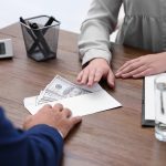 Bank teller giving money in an envelope to a customer