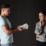 A man handing over cash to his girlfriend