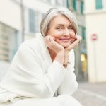 Woman in her 60s smiling on a bench
