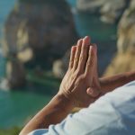 Man with praying hands near the ocean