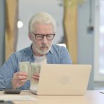 Baby boomer on his laptop with cash