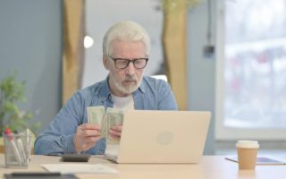 Baby boomer on his laptop with cash