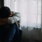 A sad man with his head on his knees