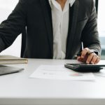 Young male work with financial papers at home count on calculator before paying taxes receipts online, planning budget glad to find chance for economy saving money, audit concepts