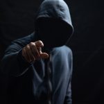 A criminal in a hoodie reaching out