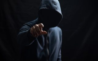 A criminal in a hoodie reaching out