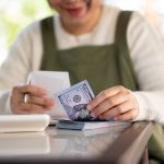 A woman paying a restaurant bill with a couple hundred dollars