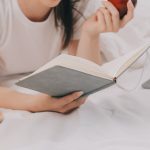 A young woman reading a book in bed