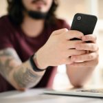 tattooed man scrolling on his smartphone