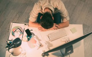 An overworked man laying his head on his desk