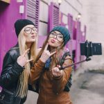 Two female friends taking a photo with a selfie stick