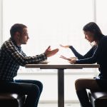 A couple sitting at a restaurant table arguing