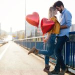 A couple in love with a pair of heart balloons