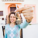 Happy woman holding keys in front of her house