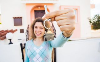 Happy woman holding keys in front of her house