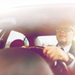 happy senior businessman driving car