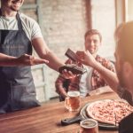Man paying for pizza at a restaurant with a friend