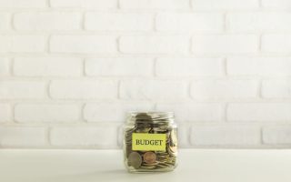 A jar filled with coins and a small sign that says "budget"