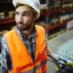 A warehouse worker wearing an orange vest