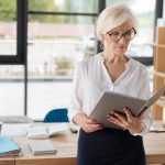 Senior female employee looking in a binder in an office