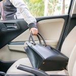 A man stealing a purse out of a car