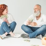 Two seniors sitting down and holding money