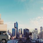 A truck with moving boxes and a city in the background