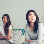 Two young female friends looking unhappy with each other